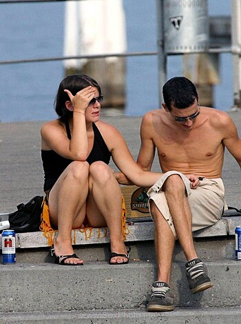 A couple of horny assholes are parked on a public bench, buck naked from the waist up, their tits hanging out for all to see.