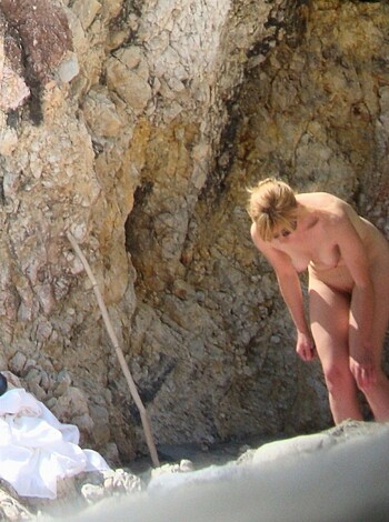 A chick stands nude by a bitchin' boulder, yelling obscenities at the camera.