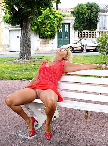 A bitch is sitting on a bench with her legs wide open, wearing a sexy red dress and fuck-me heels.