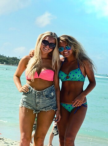 Two chicks in skimpy bikini ass-pics, lounging on the sandy shore of a fucking hot beach.