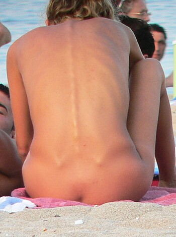 "Two dudes with bare chests and no shirts grind up on a naked babe lying down on the sand while one guy's got his ass out and the other's looking at her ass from behind."