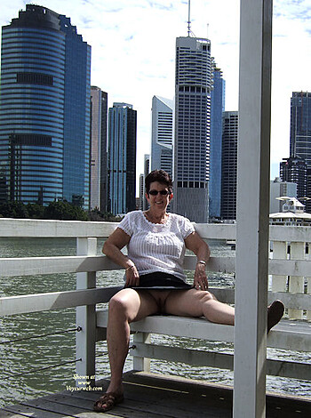 Here's your limit of 30 words: "Nude chick sunbathing her tits while looking at the city skyline from a park bench, all natural."