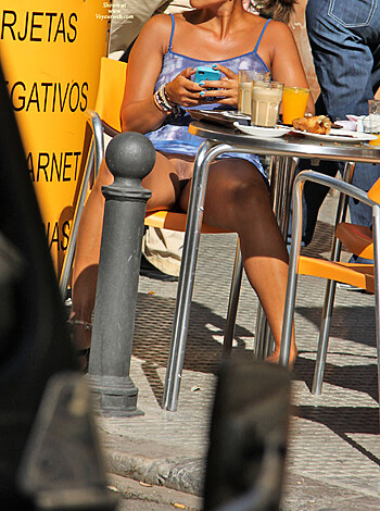 """
Hot babe in short skirt, ass and tits hanging out, smoking cigs and drinking coffee on a sunny day at an outdoor patio.
"""
