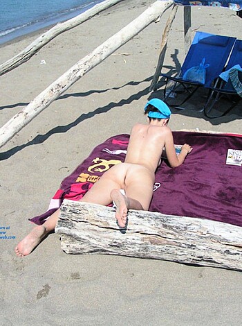 Sunbathing naked chick on the shore.