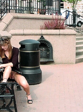 A smoking hot babe in tight black clothing sits on a bench, her hair flying wildly as she enjoys the breeze while spreading those luscious thighs wider than any man could fucking handle!