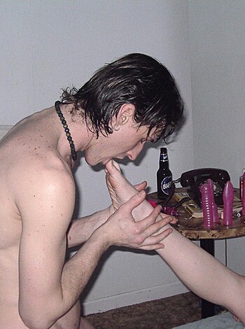 Here's the caption for this image: "Nude guy with his tongue on a chick's barefoot."