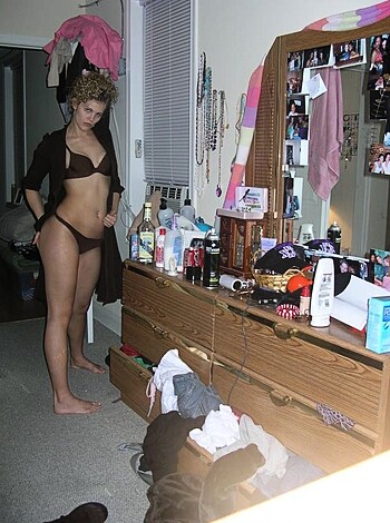 """
F*cking hot chick in tight black bikini checks out her ass in a mirror while standing naked beside a f*cked up bed with shit all over it.
"""