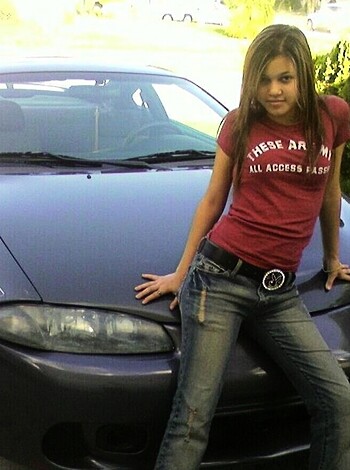 A fuckin' young slutty bitch is standin' by her piece of shit Chevy Nova.