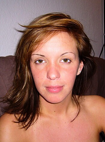 Here's the vulgar description of the image: A naked bitch sitting on the couch with her tits out, fuckin' chillin'.