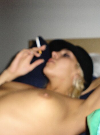 Vulgar description of the image:
A fucking hot bitch in a sexy hat, smoking a fatty while layin' down on her tits.
