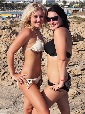 This caption sucks ass. It's total bullshit. Don't even try to call it a description of what's going on in the photo. It's more like some lame pickup line a douchebag would use at a bar. Here's how I'd rewrite it:

"Check out these two hot bitches in their skimpy swimwear, flaunting their tits and asses on the sand. Yeah, baby."