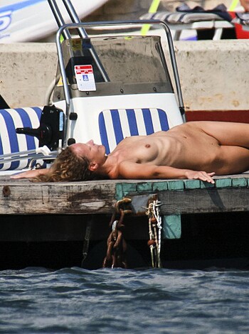 A nude broad is sunbathing on top of a yacht while her perky tits are hanging out.