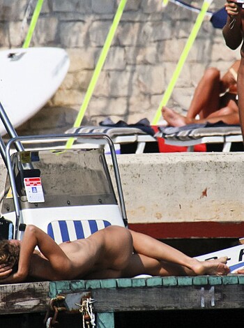A sweaty guy snaps a pic of a chick getting some sun on the beach, her tits out and everything.