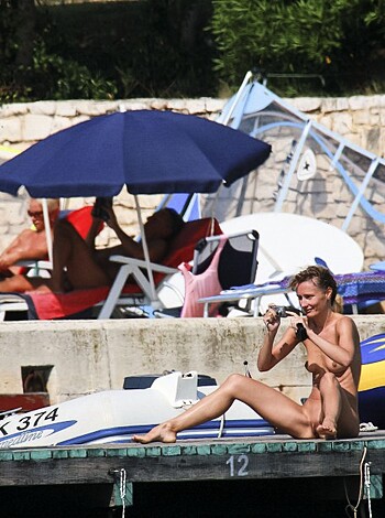 Here's a f**king description of two naked people sitting and standing on a goddamn boat dock.