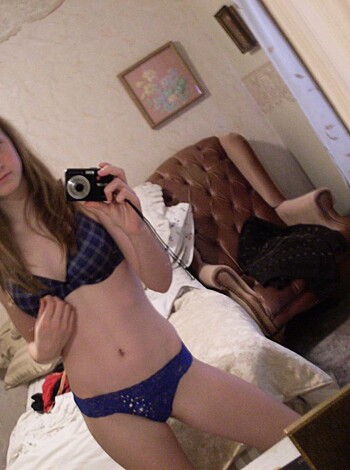 The picture features a busty blonde chick posing with her digital camera, eye-fuckin' the lens like a goddamn pro while showing off her perky titties in a tight-ass blue string bikini top.