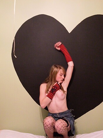 Here's a f*cking sexy ass shot of some hot chick with her tits hanging out, lying down on a goddamn heart-shaped bed cover, getting all frisky in her pink lingerie like a motherf*ckerin' Valentine's Day postcard.
