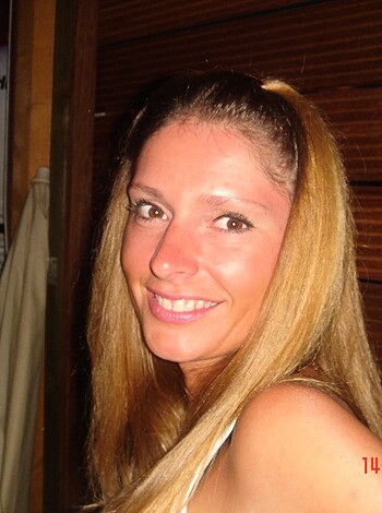 A busty blonde in a tight t-shirt grins like an idiot while posing for the camera, her big fake tits threatening to burst out of her top and spill all over the place.