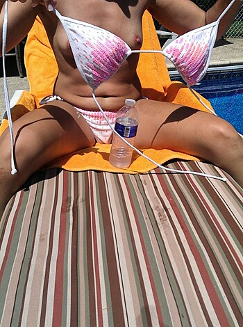 A hot brunette babe is chilling in a skimpy bikini sipping on some cocktails while laughing it up on the beach under a blazing sun.