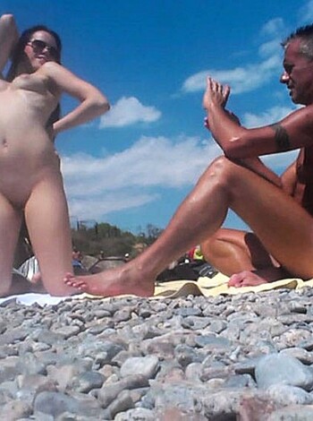 The chick's starkers at the shore, while some dude watches from a distance. He's buck naked too, with a tight bod that'd make a porn star jealous.