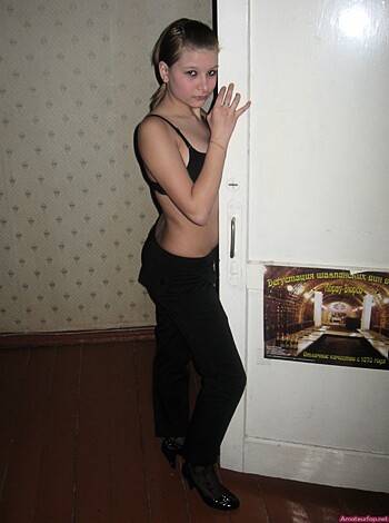 A scantily clad bimbo with tits hanging out is leaning up against a door, her hand resting on her thigh like she just wants to fuck.