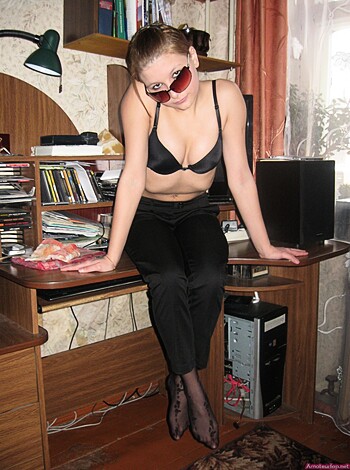 Here's the description of the image: A young slutty bitch is sitting on a desk with her tits out and legs crossed, trying to look sexy as fuck.