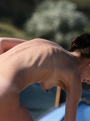 A naked chick posing next to some water, dicks on her mind.