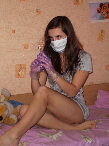 A fucking hot babe with a surgical mask and gloves on while laying down on her sick bed.
