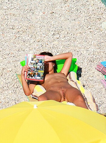 Vulgar description of the image: "You see this fucking hot bitch, right? She's got her tit fat jiggling around while she lays on some fucking beach, naked as hell. And just look at that sweet yellow umbrella, hiding her cooch like a champ. God damn."