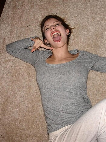 A bitch is sticking her tongue out while lying on the ground.