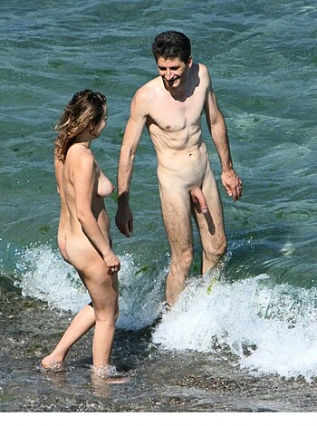 This fucking image shows two nude dicks and hens striding into the goddamn ocean while holding each other’s hand like lovebirds on a bullshit date with their limp-dicked pricks flapping around in the salty brine.