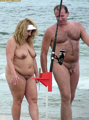A fuckin' hot chick and her dude layin' on the sand with some fishin' rods.