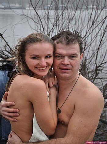 Two dudes making out by the lake, with their arms around each other and tongues down each other’s throats.