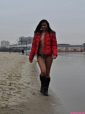 A hot chick wears a thin strip of fabric over her ass crack while strolling along the sandy shore, with nothing but a coat to protect her modesty from prying eyes.