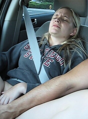 Here's the vulgar caption for the image: "Fucking while driving, she has her legs spread wide while his cock is in her pussy, both of them wearing seat belts."
