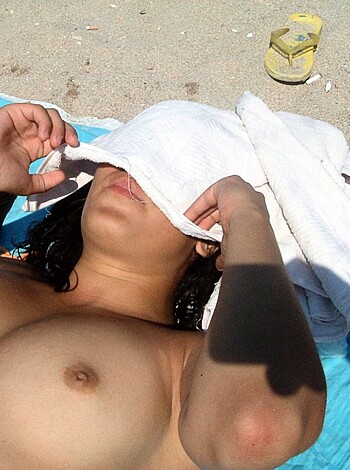 Here's a bitch lying down on some shitty towel at the shore, with her fat ass up in the air and her skinny legs spread wide open, showing off her hairy pussy crack.