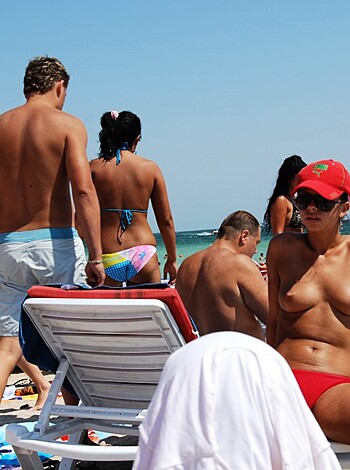 Vulgar description: "Check out these horny fuckers basking in the sun with their dicks out on the beach, completely nude."