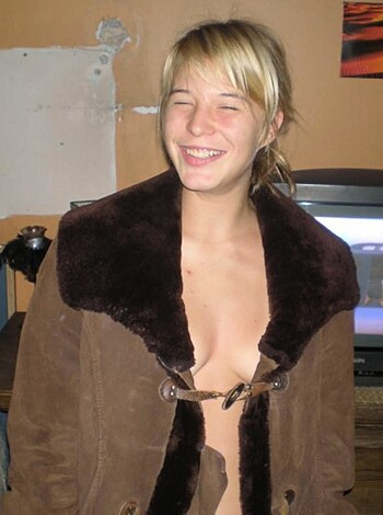 Here's the vulgar description of the image:
"Look at this naked bitch, showing off her tits in some fur coat while smiling like a motherfucker!"