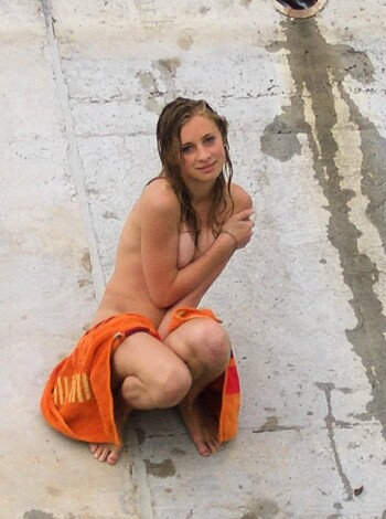 Here's a description of a vulgar and obscene image of a naked bitch sitting on the goddamn ground like some piece of shit.