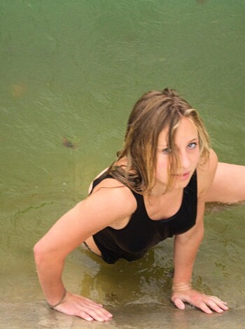 This image shows a hot babe getting her wet tits and pussy soaked by the waves crashing against her as she's down on her knees, taking a pee or shitting in the ocean for all you know, bro.