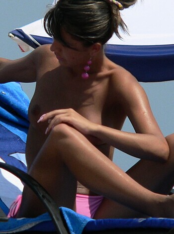 A busty chick, sunbathing in her lawn chair, with her boobs out, just chillin' at the fuckin' beach.