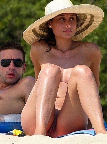 Here's a fucking picture of some stupid bitch with a goddamn straw hat sitting next to some dickhead who doesn't even have a shirt on, looking like a pair of dumbasses while they waste their time on the beach.