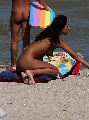 A topless bitch chillin' on the sandy shoreline with her tits hanging out and exposing her fucking boobs, flaunting her shit at anyone who wants a peek.