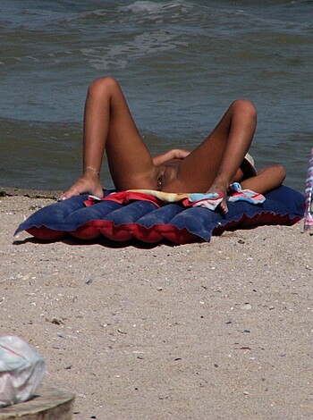 """
Take a fuckin' look at this bitch, lying ass-up on a fuckin' beach towel, totally nude and ready for some serious dick-sucking action! This is the definition of a fine piece of ass, motherfuckers. You wanna see some tits? She ain't wearing no fuckin' top, ya dumb shit! And her ass? Holy fuck, it's like a goddamn piece of art, man. I swear to Christ, if I were there, I'd be all up in that bitch's business, givin' her some serious cock-lovin'. She's fucking perfect, ya feel me?""