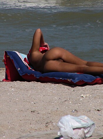 The fuckin' image shows a titty chick loungin' on a beach chaise with her rack out for all to see.