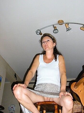 A fucking naked bitch sits on her ass cheeks in a bare wooden room with a motherfucking ceiling light.