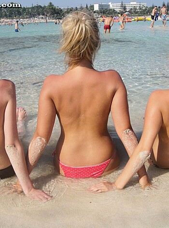 Four busty bitches with titties out sunning themselves on the sand.
