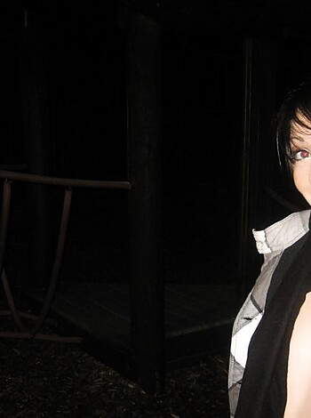 """
Topless broad in the dark with jungle gym behind her.
"""