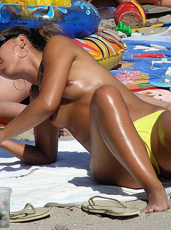 "This image is of a hot brunette lying on her back, taking the sun with nothing but a bikini bottom covering her privates. She's rockin' a yellow string bikini bottom while shades protect her eyes from the harsh rays. It's an eye-catching shot."