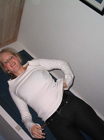 This image shows a busty blonde chick with tits out and a smile on her face.