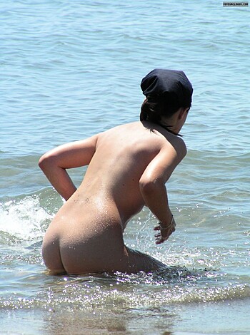 Here's the fucking shit-show of a bitch posing with her bare tits bobbing up and down in those salty cock-sucker waves.